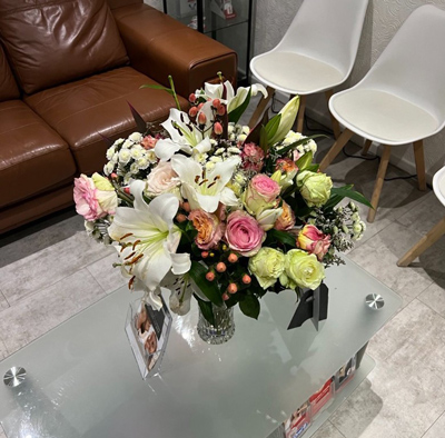 a vibrant flower arrangement featuring roses lilies and other blooms displayed on a coffee table in a contemporary setting with eight shades of color